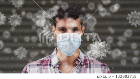 Standing man in plaid shirt, surgical mask in front of gray shutter with floating virus particles Standing man in plaid shirt, surgical mask in front of gray shutter with floating virus particles 132982719