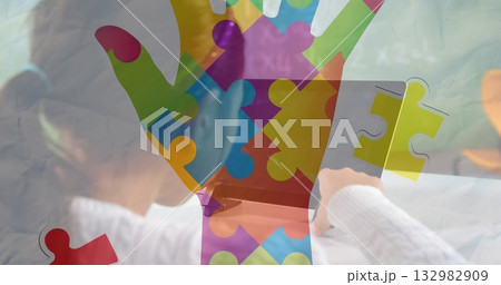 Chinese girl in white sweater tapping tablet on white desk at home, with colorful puzzle overlay 132982909