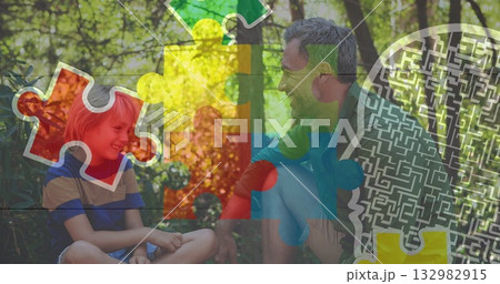 Smiling father and son sharing moment on sunlit clearing, with colorful puzzle maze graphics 132982915