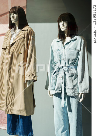 Two female mannequins dressed in casual trench coat and denim outfit in shop window Two female mannequins dressed in casual trench coat and denim outfit in shop window 132983172
