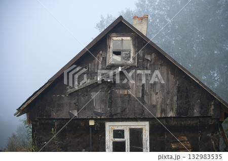 Old Weathered Shack With Charred Wood Exterior in Foggy Rural Landscape at Dusk Old Weathered Shack With Charred Wood Exterior in Foggy Rural Landscape at Dusk 132983535