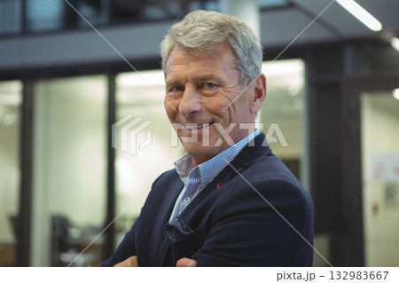 Senior male professional standing in office with partitions, wearing navy blazer with pocket square 132983667