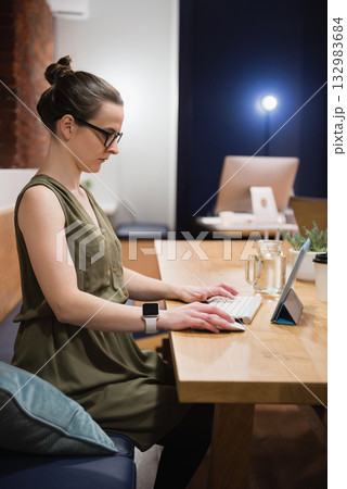 Female professional typing on tablet with keyboard, coffee cup at office by brick wall, copy space Female professional typing on tablet with keyboard, coffee cup at office by brick wall, copy space 132983684