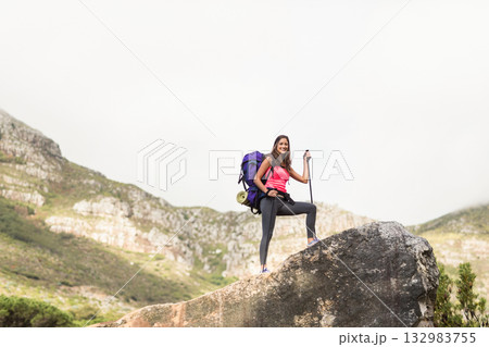 woman hiker standing on mountain trail in pink top carrying purple pack, trekking poles, copy space woman hiker standing on mountain trail in pink top carrying purple pack, trekking poles, copy space 132983755