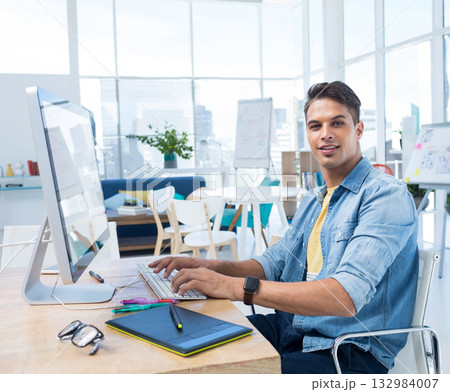 Mid adult man working on graphics tablet and desktop computer at modern office desk, copy space 132984007