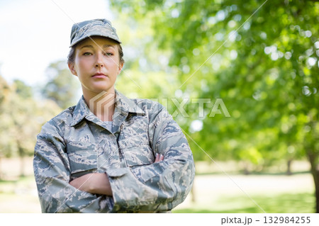Mid adult female soldier standing with arms crossed in grassy park in camouflage uniform Mid adult female soldier standing with arms crossed in grassy park in camouflage uniform 132984255