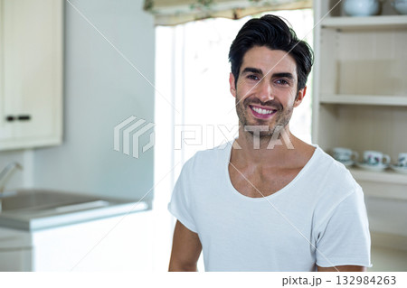 Man standing in home kitchen by sink and open shelves under floral valance window, copy space Man standing in home kitchen by sink and open shelves under floral valance window, copy space 132984263