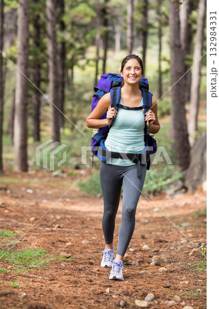 Female hiker in late twenties walking along conifer trail wearing sportswear and carrying backpack 132984331