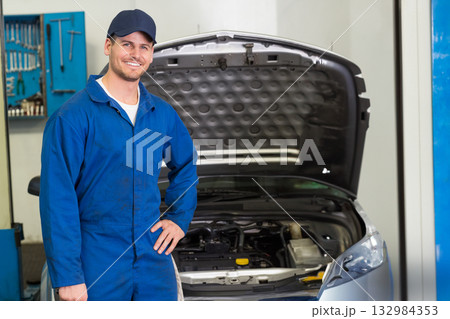Male mechanic standing beside silver car with open hood at garage showing engine, tools, copy space Male mechanic standing beside silver car with open hood at garage showing engine, tools, copy space 132984353