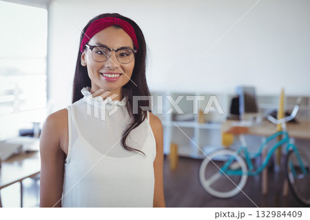 Mid adult woman smiling in office wearing dark rimmed eyeglasses and red headband with teal bicycle 132984409