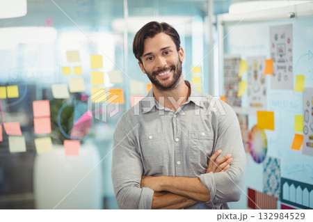 Man in gray shirt writing on glass wall in office with sticky notes and diagrams 132984529