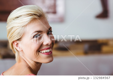 Woman smiling, looking over shoulder in spa room wearing pink robe with rolled towels, copy space 132984567