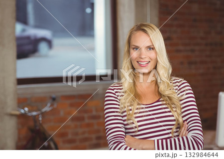 Woman in striped top smiling in office by bicycle and window showing car, copy space 132984644