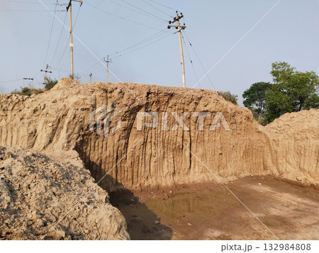 Clay-lined pit dug into the ground for foundation or construction work with vertical soil walls rural earthwork and excavation site Clay-lined pit dug into the ground for foundation or construction work with vertical soil walls rural earthwork and excavation site 132984808