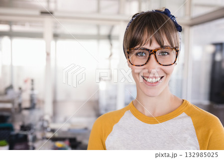 Woman standing at open plan office wearing fabric headband and tortoiseshell eyeglasses, copy space 132985025