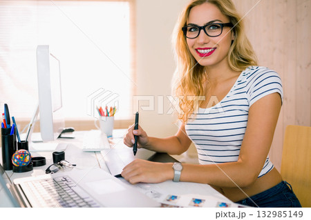 Woman working on digital design in home office wearing striped top with graphics tablet, copy space 132985149