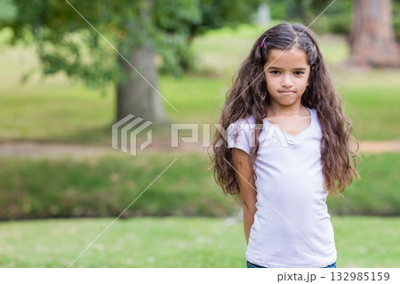 Girl standing in well-kept public park with pink hair clip in hair near tree, copy space 132985159