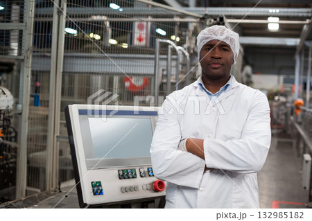 Mid adult African American man in lab coat inspecting touchscreen panel on plant floor, copy space 132985182