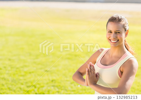 Female practicing yoga pose wearing pale yellow tank top, peach sports bra at park, copy space Female practicing yoga pose wearing pale yellow tank top, peach sports bra at park, copy space 132985213