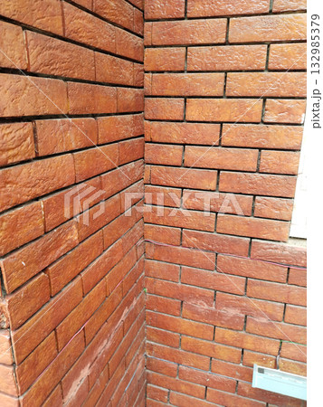 Close-up view of colonial-style red brick wall showing aged texture, earthy tone, and traditional handmade construction detail in natural light, perfect for vintage architecture background 132985379