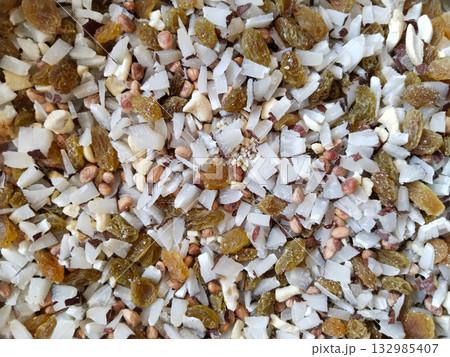 Assorted dry fruits including coconut flakes, chironji, and raisins placed in a heap without any halwa, close-up of raw Indian sweet toppings for traditional desserts 132985407