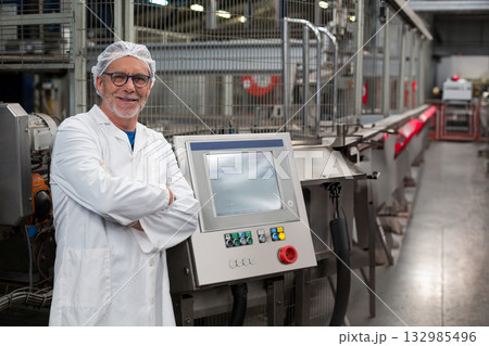Senior technician wearing lab coat crossing arms at touchscreen panel on conveyor belt, copy space Senior technician wearing lab coat crossing arms at touchscreen panel on conveyor belt, copy space 132985496