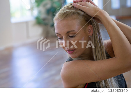 Woman in athletic tank top pulling right arm across chest at dance studio, copy space Woman in athletic tank top pulling right arm across chest at dance studio, copy space 132985540