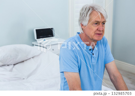 Senior man sitting on edge of bed in bedroom, tapping digital tablet screen, copy space Senior man sitting on edge of bed in bedroom, tapping digital tablet screen, copy space 132985703