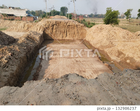 Clay lined pit dug into the ground for foundation or construction work with vertical soil walls rural earthwork and excavation site 132986237