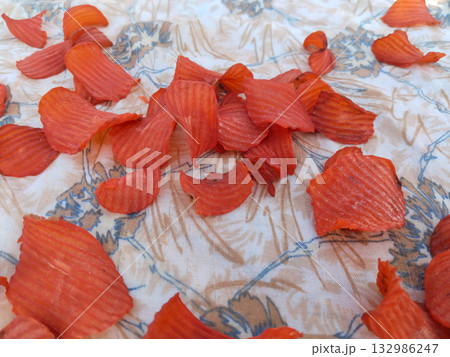 Sun-drying steamed spiced potato chips on cloth under open sky in rural India during traditional food preservation process 132986247