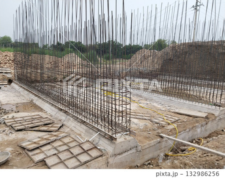 Side view of canal bridge construction site showing reinforced steel bars, concrete shuttering, and deep foundation trenches as part of large-scale civil engineering and infrastructure project 132986256