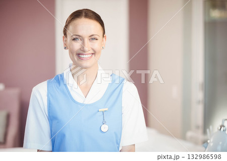 Female nurse smiling near bedside table in hospital room with badge, fob watch and medical device Female nurse smiling near bedside table in hospital room with badge, fob watch and medical device 132986598