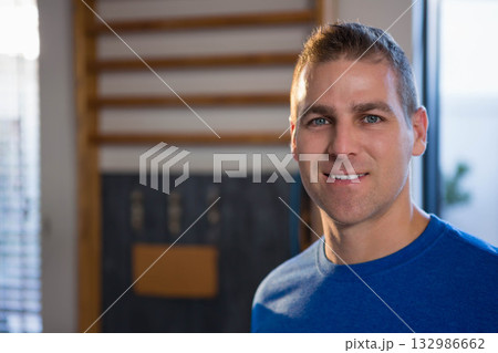 Man standing in gym wearing blue t-shirt near wooden stall bars with metal hooks, copy space Man standing in gym wearing blue t-shirt near wooden stall bars with metal hooks, copy space 132986662
