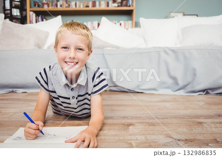 School-age boy wearing striped polo drawing with blue marker on paper in living room School-age boy wearing striped polo drawing with blue marker on paper in living room 132986835