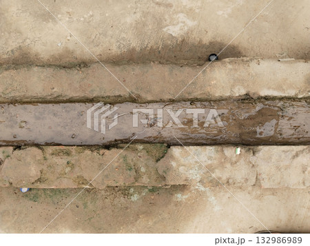 Small drainage channel made with red bricks in rural setting showing simple village water management system and traditional handmade drainage structure on earthy ground Small drainage channel made with red bricks in rural setting showing simple village water management system and traditional handmade drainage structure on earthy ground 132986989