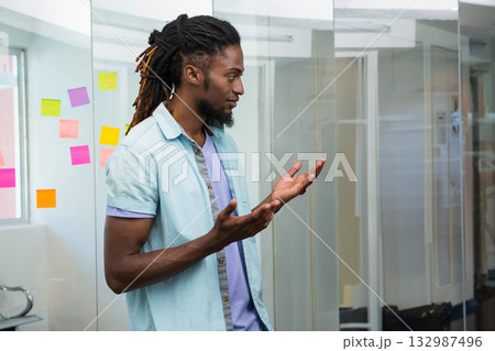 African American man gesturing while brainstorming in office with colorful sticky notes, copy space African American man gesturing while brainstorming in office with colorful sticky notes, copy space 132987496