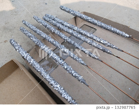 Close-up of multiple unused Diwali sparklers scattered on ground surface, unboxed fireworks with colorful sticks lying on floor before use during Indian festive preparation scene 132987765
