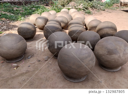 Unfired clay earthen pot placed under direct sunlight for drying, showcasing traditional rural pottery in natural environment before firing process, handmade Indian terracotta craft Unfired clay earthen pot placed under direct sunlight for drying, showcasing traditional rural pottery in natural environment before firing process, handmade Indian terracotta craft 132987805
