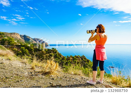 Woman with camera take travel photo on sea shore 132988750