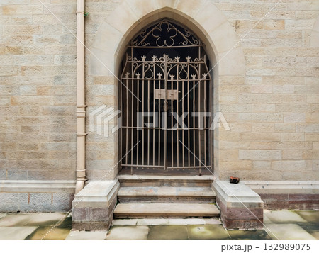 Old iron gate with decorative arch design in stone wall entrance, closed rusty gate with vintage architecture style, ancient doorway steps and heritage structure exterior with secure locked barrier Old iron gate with decorative arch design in stone wall entrance, closed rusty gate with vintage architecture style, ancient doorway steps and heritage structure exterior with secure locked barrier 132989075