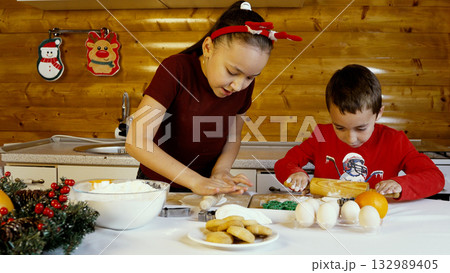 The children are baking and decorating Christmas cookies in the kitchen The children are baking and decorating Christmas cookies in the kitchen 132989405
