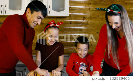 The family is happily baking Christmas cookies together in the kitchen The family is happily baking Christmas cookies together in the kitchen 132989406
