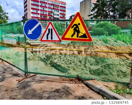 Road signs - sidewalks are being repaired and paving stones are being laid. Road work and detour signs on the city road 132989745