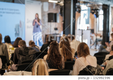 Speaker on stage presents at conference to engaged audience during indoor event 132992396