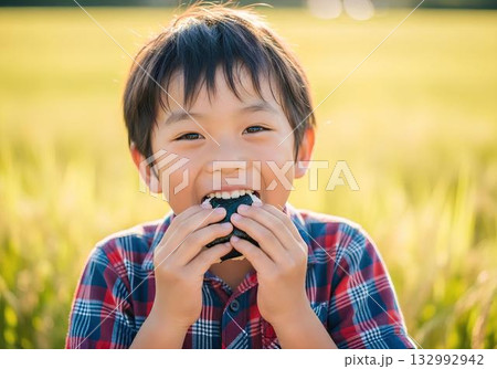 おにぎりを美味しそうに食べている少年 132992942