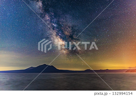 澄んだ夜空に広がる天の川と山影のシルエット 132994154