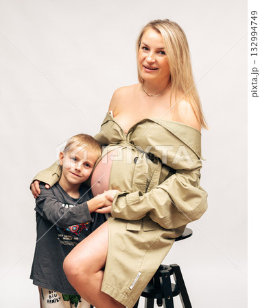 Warm family portrait of pregnant woman with her son in bright studio setting. Soft light, neutral tones and emotional connection perfect for family and maternity concepts Warm family portrait of pregnant woman with her son in bright studio setting. Soft light, neutral tones and emotional connection perfect for family and maternity concepts 132994749