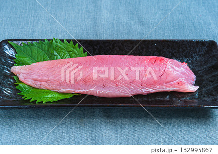 キメジマグロの短冊, 黒い長皿に盛られた生のマグロと大葉 132995867