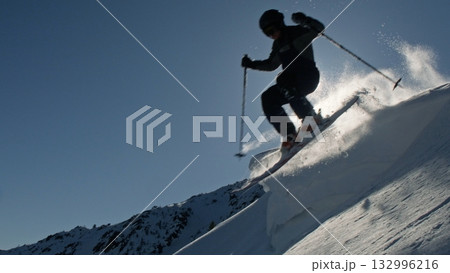 Professional skier jumping from snowy mountain ridge in bright sunlight Professional skier jumping from snowy mountain ridge in bright sunlight 132996216