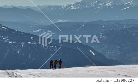 Mountaineers standing on snowy mountain ridge enjoying scenic view Mountaineers standing on snowy mountain ridge enjoying scenic view 132996227